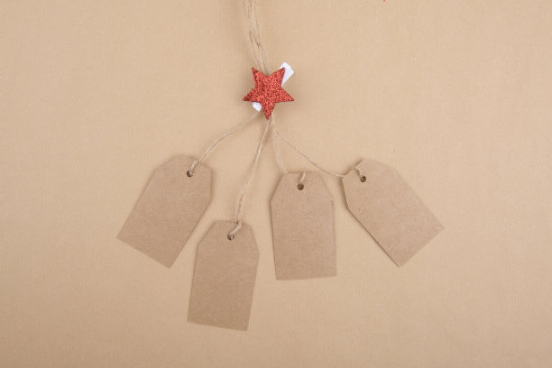 绳子上挂着四张牛皮纸标签，绳子上用晾衣夹装饰，牛皮纸上有一颗红色的圣诞星星图片下载