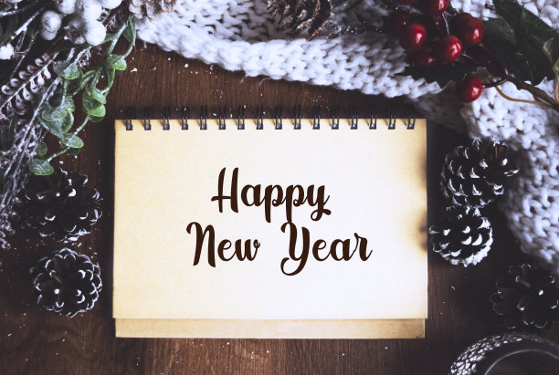 节日装饰品，圣诞蜡烛，装饰树枝和一个笔记本上写着新年快乐的木头桌子，俯视图。圣诞节或冬季的规划概念。平的。图片下载