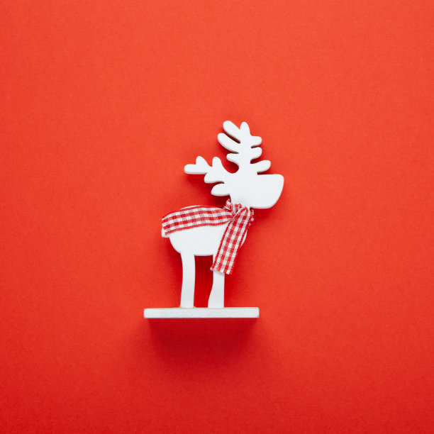 圣诞装饰，玩具白色的鹿在格子围巾在红色的背景，复制空间。喜庆、新年的概念。广场,平。最小的风格。俯视图图片下载