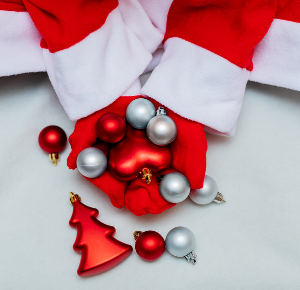 戴着红色手套的手拿着红色和银色的圣诞球在灯光背景上。圣诞节，新年，圣诞老人，2021年。前视图。图片下载