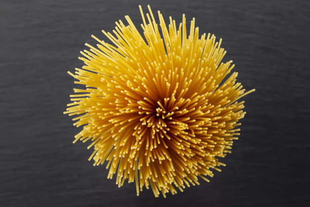 黑色背景上的黄色长面条。意大利菜和菜单概念。空间的文本。图片下载