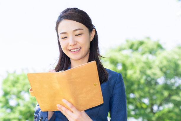 一个在户外填写日程表的亚洲女人图片下载