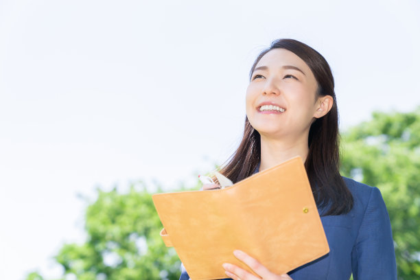 一个在户外填写日程表的亚洲女人图片下载