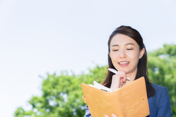 一个在户外填写日程表的亚洲女人图片下载