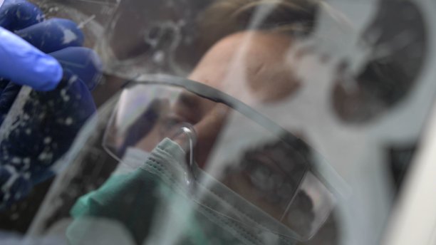 医生戴着外科口罩、眼镜和手套在触摸屏上查看x光图像图片下载