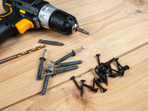 螺丝钉和销钉背景上有一个螺丝刀，选用不同的螺丝钉和销钉用于不同材料的墙面和表面图片下载