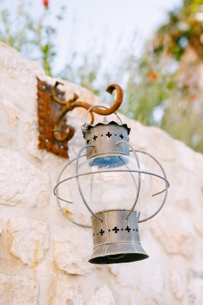 石头墙上生锈的钩子上挂着一个旧金属灯笼。图片下载