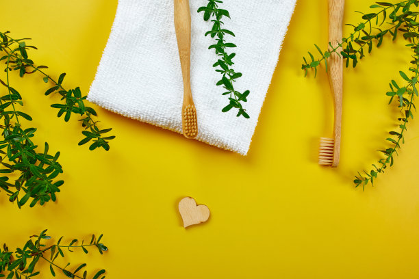 竹制的牙刷和耳棒，黄色纸上的绿叶图片下载