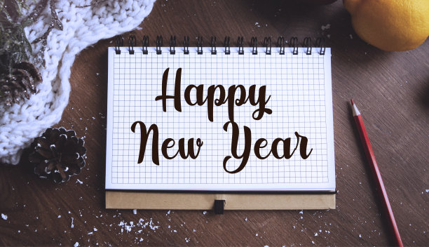 节日装饰品，圣诞蜡烛，装饰树枝和一个笔记本上写着新年快乐的木头桌子，俯视图。圣诞节或冬季的规划概念。平的。图片下载