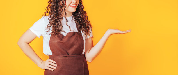 穿着咖啡师制服的年轻女子指着黄色背景上的一边图片下载