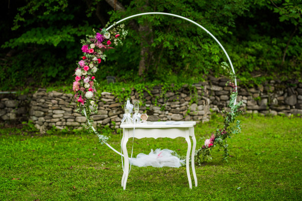 粉色和白色鲜花装饰的圆形婚礼拱门和一张婚礼用的桌子图片下载