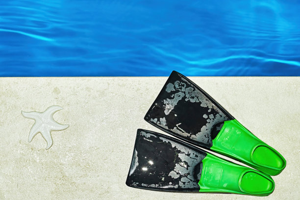 池边瓷砖上五颜六色的孩子们的脚蹼和海星。浮潜和户外活动图片下载