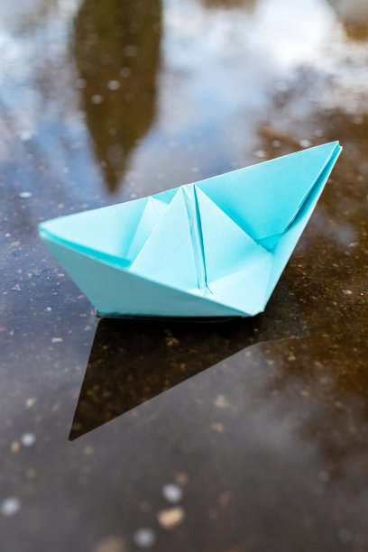 一艘蓝色的纸船漂浮在水面上。在户外。秋天的季节。带有副本空间的贺卡。领导的概念。自由的概念图片下载