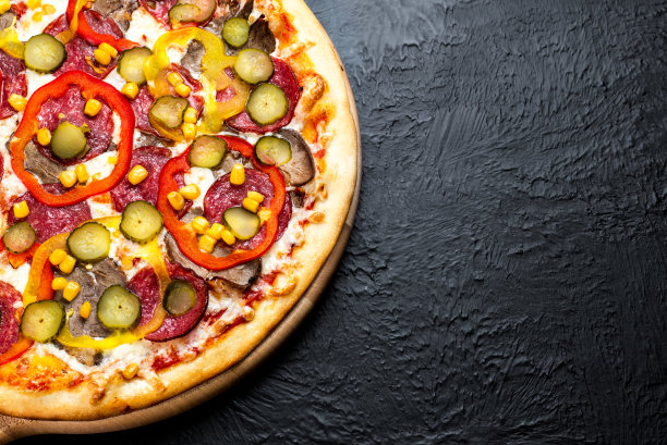 黑色背景的墨西哥披萨，以番茄为基础，配以马苏里拉奶酪、意大利腊肠、牛肉、甜椒、玉米和淡盐黄瓜图片下载