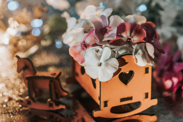 木制家具。玩具屋家具和花。儿童木制家具和花园里的花。木制玩具被精致的花朵包围着图片下载