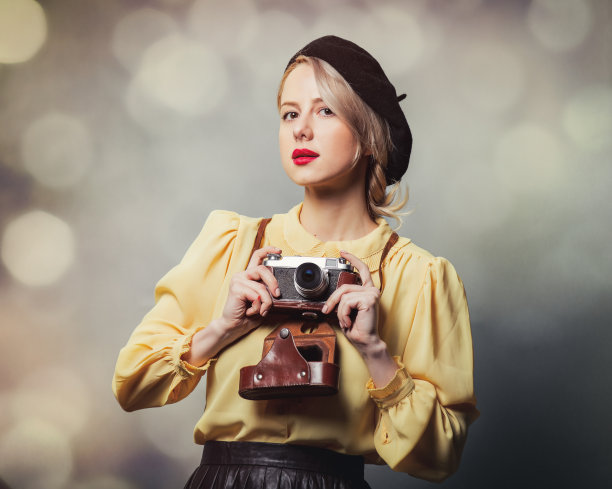 漂亮的女孩穿着复古的衣服和相机在灰色的背景图片下载