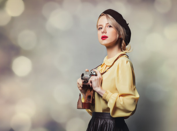 漂亮的女孩在复古的衣服与照片相机在灰色的背景图片下载