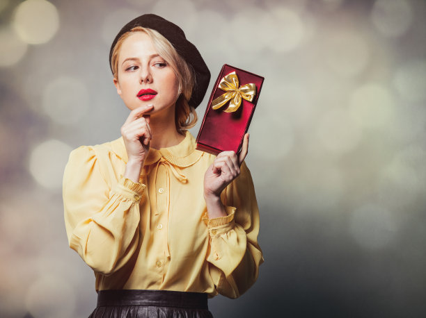 漂亮的女孩穿着复古的衣服，在灰色的背景上带着礼物图片下载