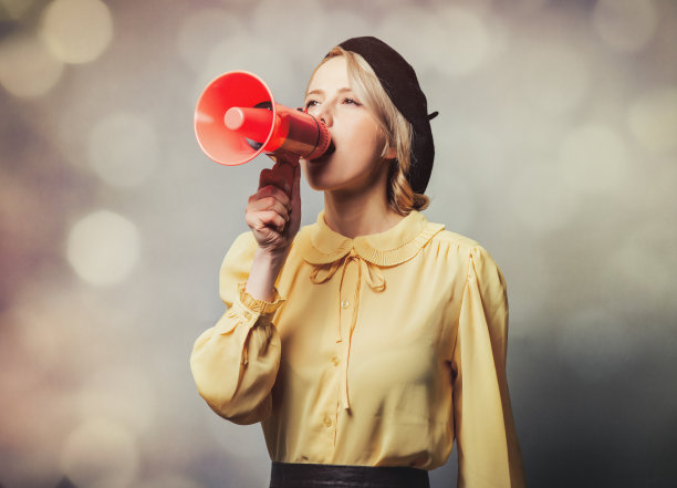 穿着复古衣服的漂亮女孩，灰色背景上放着扩音器图片下载