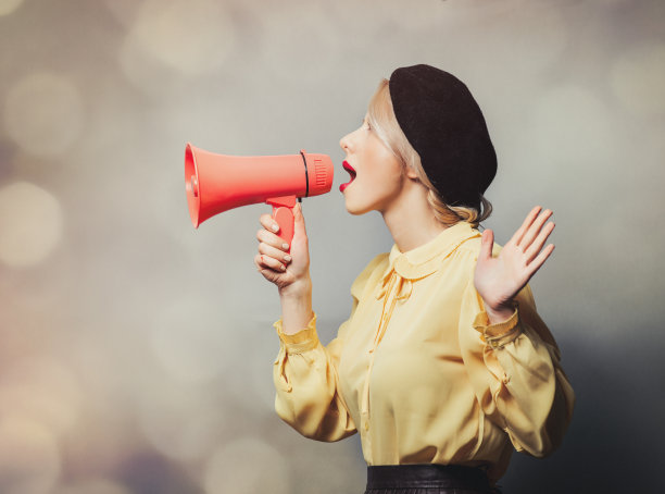 穿着复古衣服的漂亮女孩，灰色背景上放着扩音器图片下载