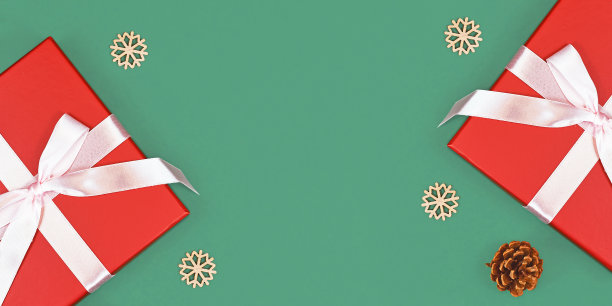 横幅与红色的圣诞礼盒丝带，松果和木制雪花装饰在绿色的背景两侧图片下载