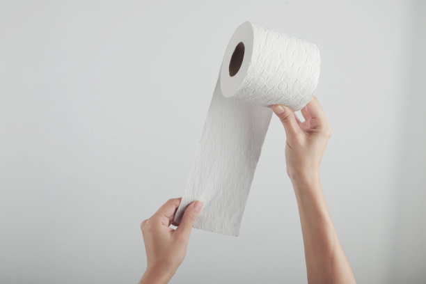 手拿白色卫生纸卷在灰色的背景图片下载