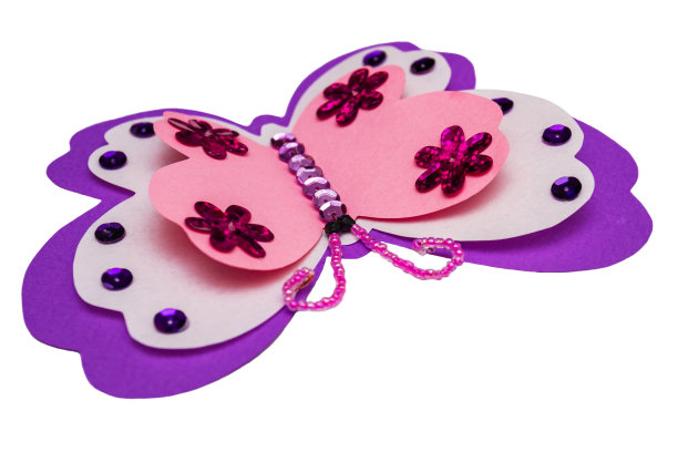 应用热熔胶枪。彩色纸制成的粉红色蝴蝶，多色亮片，亮片和珠子孤立在白色背景上。特写镜头,有选择性的重点图片下载