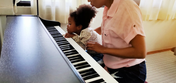 母亲在假期在家教和学弹钢琴。图片下载