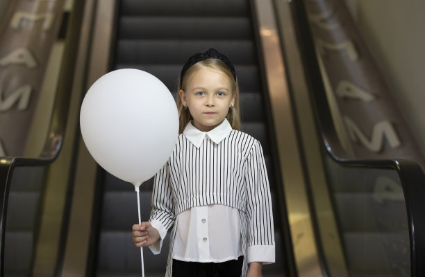 一个带着白色气垫的悲伤小女孩站在地铁的尽头。图片下载