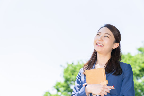 一个在户外填写日程表的亚洲女人图片下载