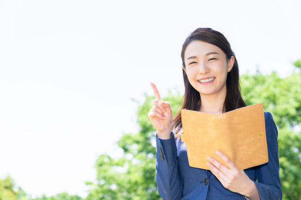 一个在户外填写日程表的亚洲女人图片下载