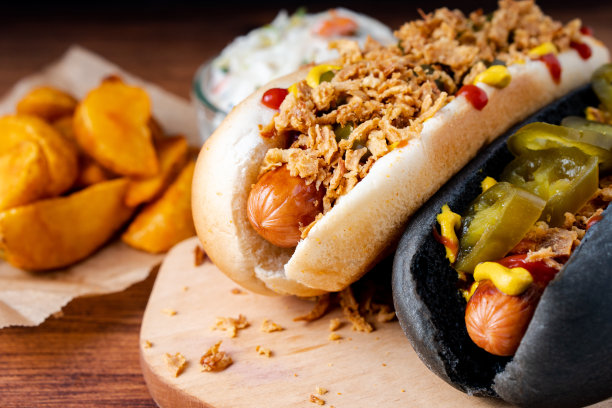 美国传统快餐热狗，新鲜的有机面包，小面包，白小麦和黑炭香肠，番茄酱，芥末配烤洋葱，泡菜，薯条，卷心菜沙拉图片下载