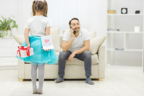 小女孩把礼物和明信片藏在身后给父亲的照片。图片下载