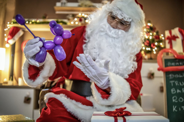 圣诞老人通过视频电话向孩子们展示礼物和气球人物——圣诞老人制作小狗形状的气球礼物并在网上展示——圣诞老人在线——气球模型图片下载