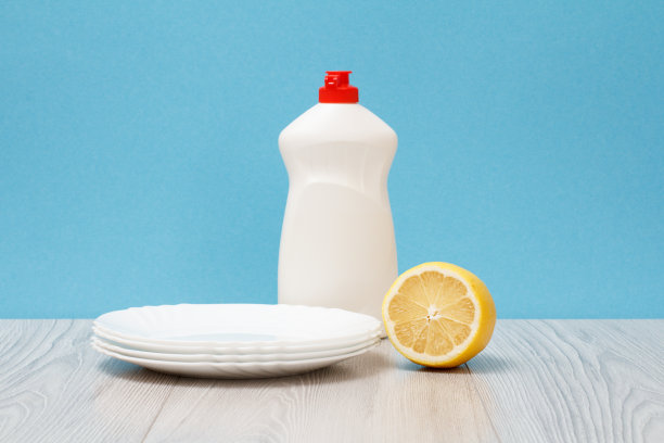 一瓶洗碗液，盘子和蓝色背景的柠檬。图片下载