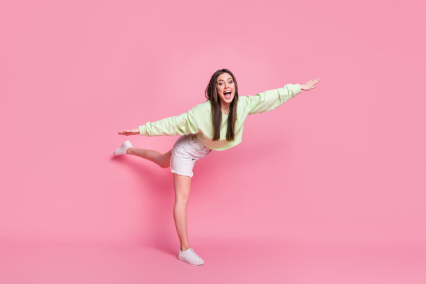 热情开朗的少女的全长照片手举起腿印象深刻做体操燕子运动穿好看的衣服鞋孤立在柔和的颜色背景图片下载