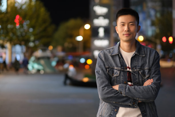 一个自信的亚洲年轻人晚上在现代城市图片下载
