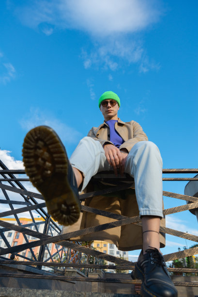 底部的观点，一个时尚的年轻人在秋天的衣服坐在楼梯上图片下载