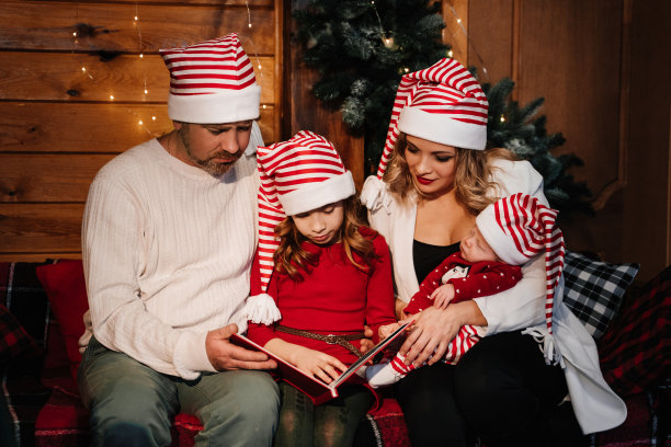 一家人在圣诞树旁看着相册里的照片图片下载