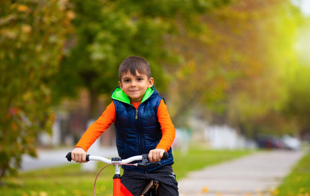 晴朗的秋日。在城市公园里骑自行车的男孩。放松和娱乐的概念花时间。照片有很多空白图片下载