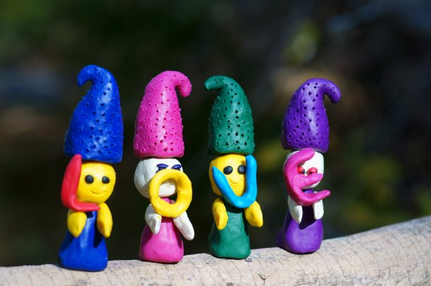 四个用橡皮泥制成的童话故事中的小矮人在森林里的彩色背景上。图片下载