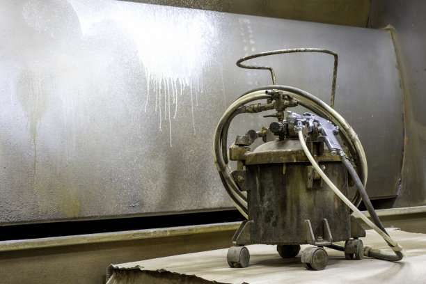 油漆压力罐，包裹着空气管和油漆到喷枪，放在油漆房的一张桌子上。图片下载