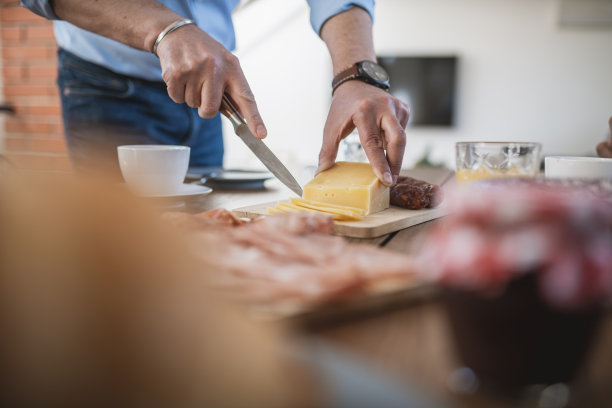 男人在早午餐桌上切奶酪的特写图片下载