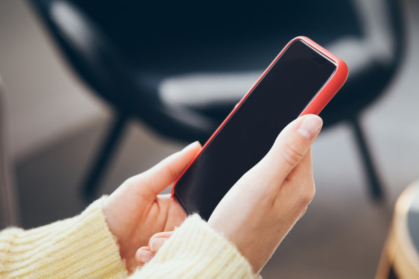 近距离照片的女人手拿着手机在红色的情况下，使用手机应用程序。图片下载