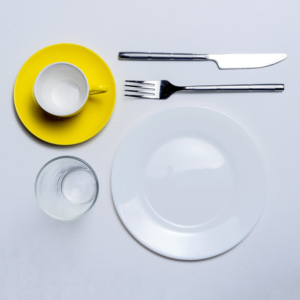 咖啡杯，叉，叉，刀和杯子在一张白色的桌子上。图片下载