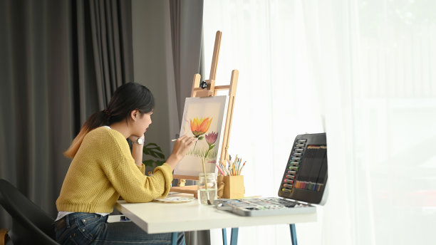一位年轻的女艺术家坐在她的工作空间里，在家里创作绘画。图片下载