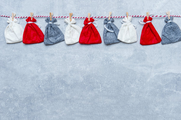 降临历在灰色的墙壁背景。在灰色的背景上，圣诞袋挂在绳子上图片下载