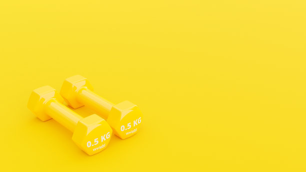 黄色哑铃在粗糙的黄色表面背景上。图片下载