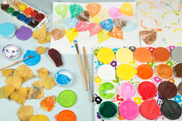 儿童桌上放着手指画和水彩画。画在纸上的秋叶印记。鼓励儿童创造力的玩具。图片下载