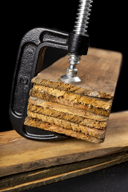 粘木用的小的黑色细木工夹。在车间工作的木工配件。黑暗的背景。图片下载